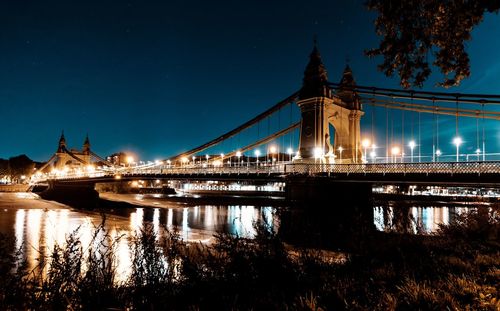 Illuminated bridge over river at night