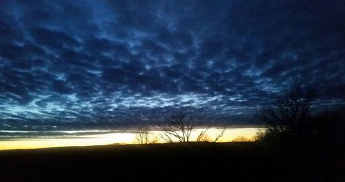 Scenic view of silhouette field against dramatic sky