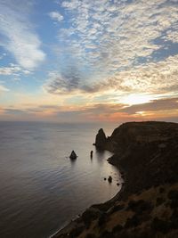 Rocks by sea against sky during sunset