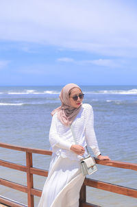 Portrait of woman standing at beach against sky