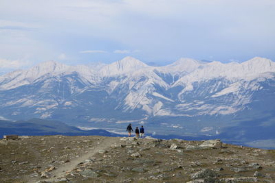 Rear view of men walking on mountain against sky