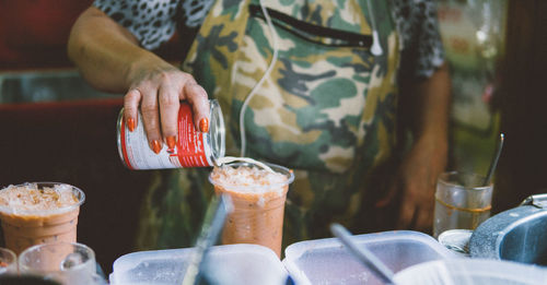 Midsection of woman holding drink on table