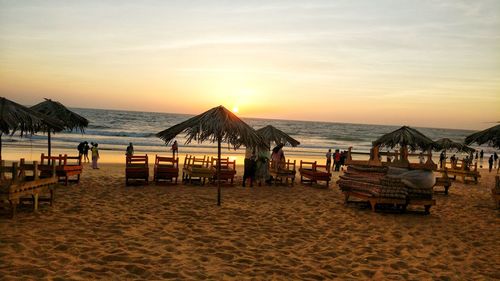 People at beach against sky during sunset