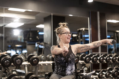 Happy woman on wheelchair training in gym