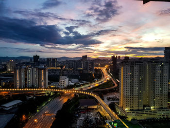 High angle view of illuminated street amidst buildings against sky during sunset