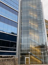 Low angle view of glass building against sky