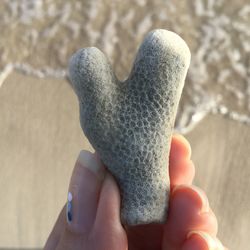 Close-up of hand holding stone at beach 