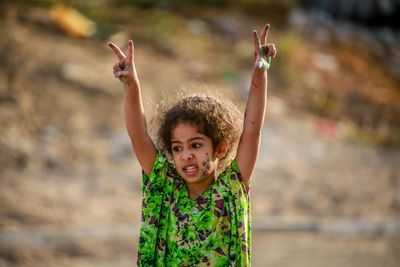 Girl showing peace signs while standing outdoors