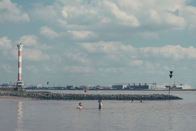 People on beach against cloudy sky