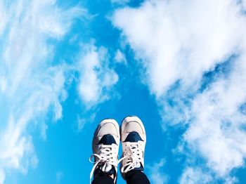 Low section of man wearing shoes against blue sky