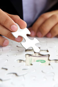 Midsection of businessman solving jigsaw puzzle