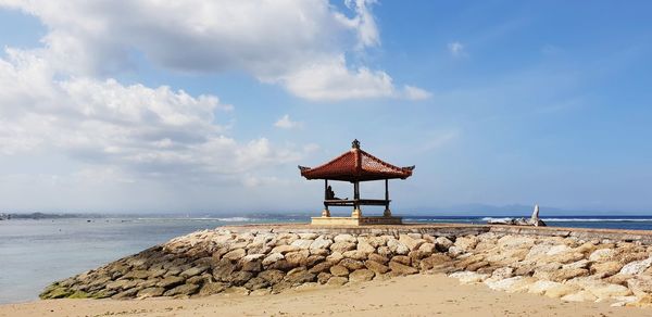 Pagoda style hut on beach against sky