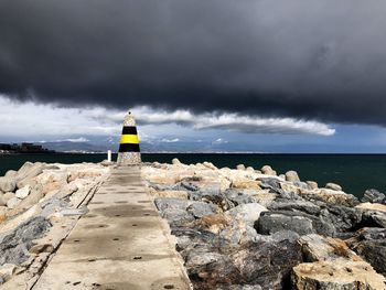Rear view of man on rock by sea against sky