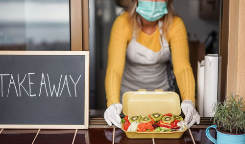 Young woman preparing takeaway healthy food inside restaurant during coronavirus - focus on salad