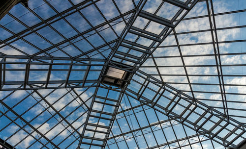 Low angle view of cloudy sky seen through greenhouse