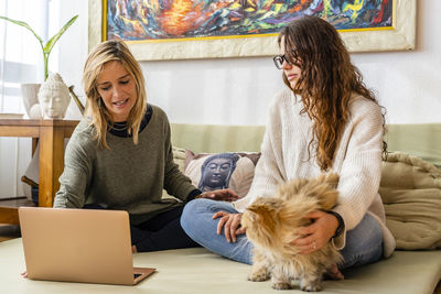 Young woman using phone while sitting on laptop