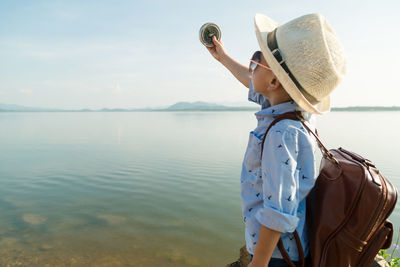 Side view of woman in sea against sky