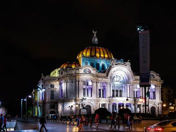 People at illuminated temple against sky at night