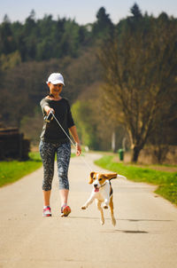 Full length of woman with dog walking on footpath