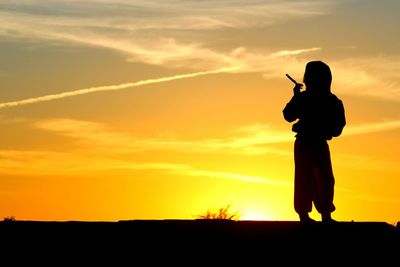 Silhouette man photographing at sunset