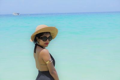 Portrait of woman wearing sunglasses standing against sea