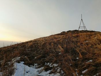 Snow covered land against sky during sunset