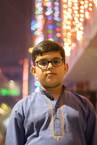 Portrait of boy standing against illuminated lights