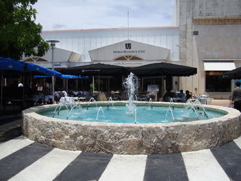 Fountain in swimming pool against buildings in city