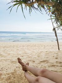 Low section of woman relaxing on beach