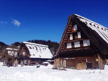 Houses on snow covered field against clear sky