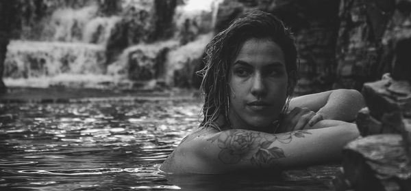 Side view of tattooed young woman looking away while swimming in lake