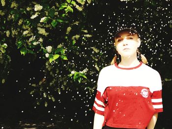Portrait of boy standing by plants against trees