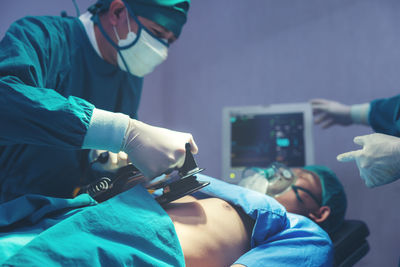 While performing medical surgery inside the operating room, a doctor and nurse use a defibrillator.