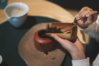 High angle view of person putting food in teapot