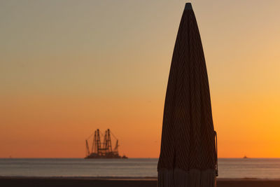 Silhouette ship on sea against sky during sunset