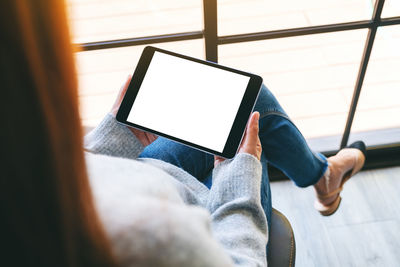 Midsection of woman using digital tablet sitting at home