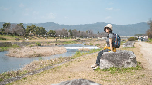 Portrait of young woman standing on field against sky