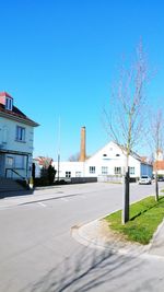 Street by buildings against blue sky