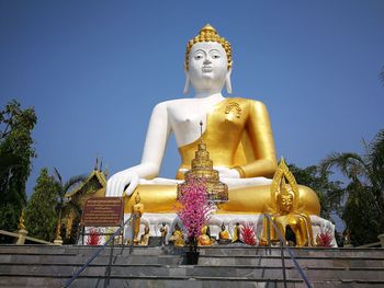 Low angle view of statue against temple against clear sky