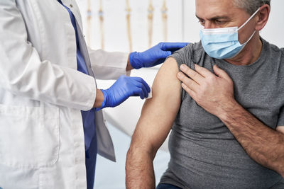 Midsection of doctor injecting syringe to patient