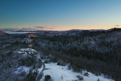 Snow covered landscape against sky during sunset