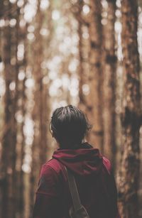 Rear view of woman with arms raised in forest