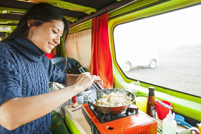 Woman cooking inside of camper van at remote location in iceland