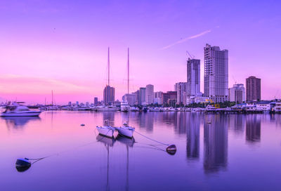 Sailboats in city against sky during sunset