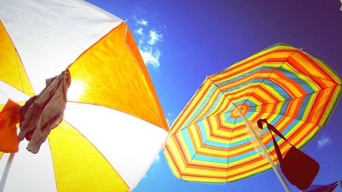 Low angle view of multi colored flags against blue sky