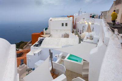 View of colorful houses of oia on a rare rainy day with pool, santorini island, greece