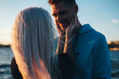 Woman embracing man against blue sky