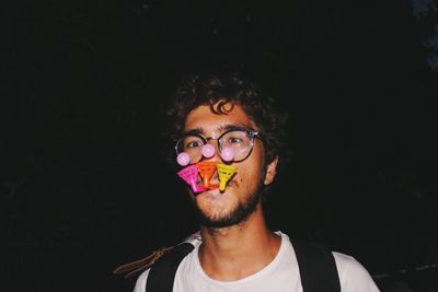 Portrait of man holding toy in mouth while standing outdoors at night