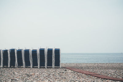 Lounge chairs at beach against clear sky