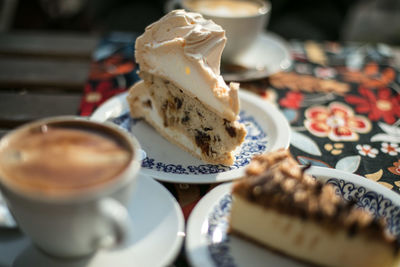 Cheesecakes in plates by coffee cup on tablecloth